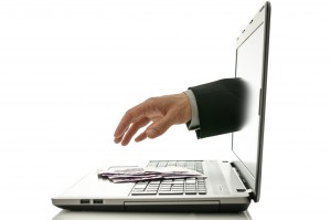 20213920 - hand reaching out of laptop screen to steal ones money.