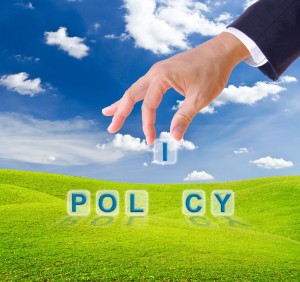 9943550 - business man hand made policy word buttons on green grass meadow